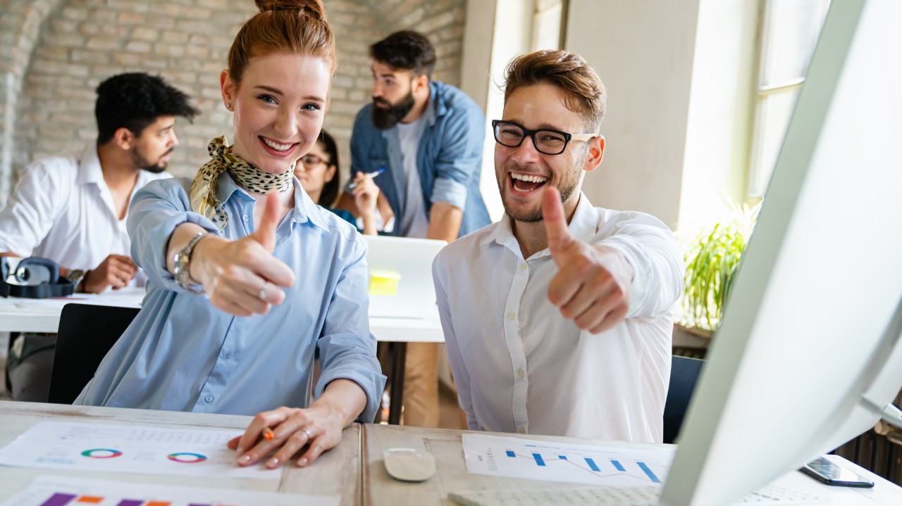 Dos personas sonriendo sacando el pulgar hacia arriba
