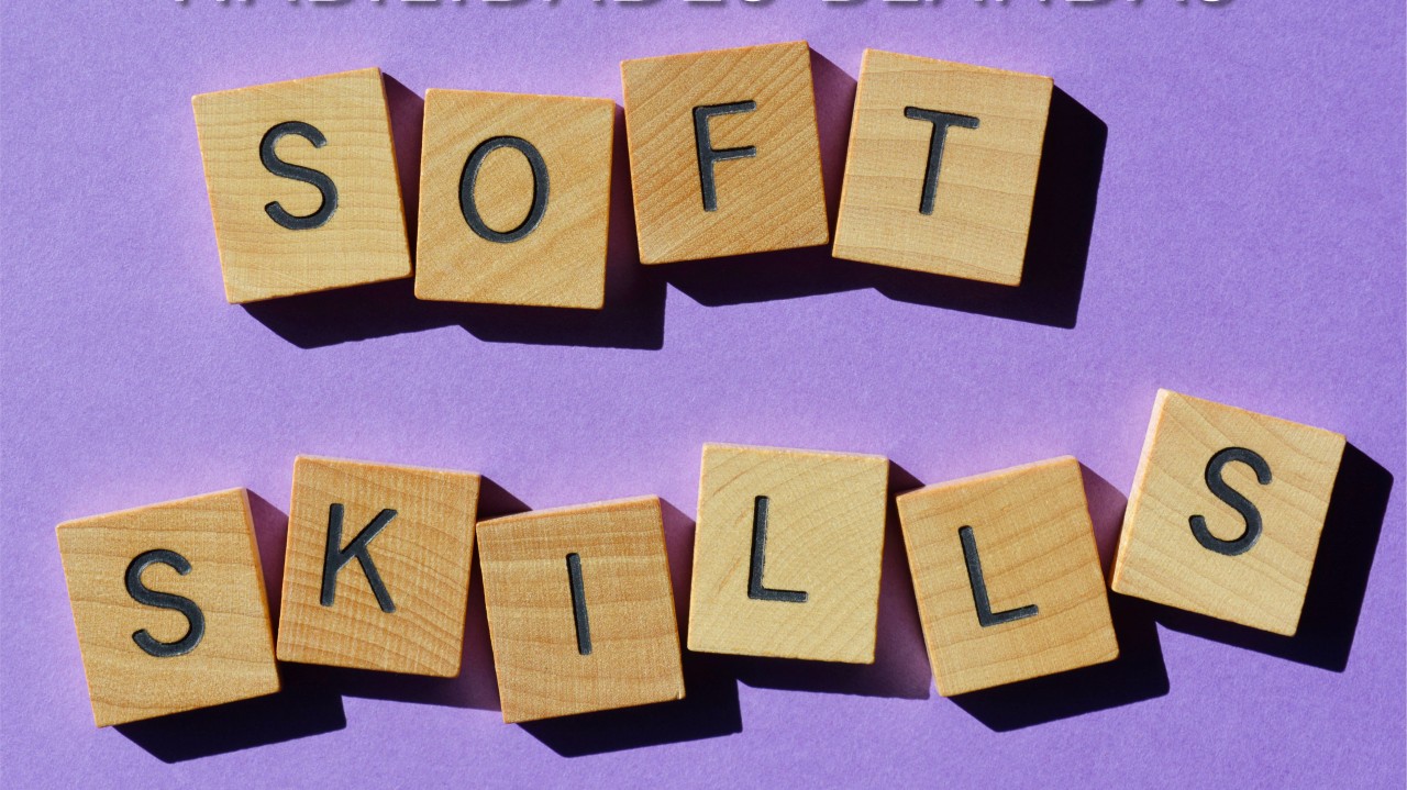 Bloques de madera que forman las palabras "soft skills" sobre un fondo morado