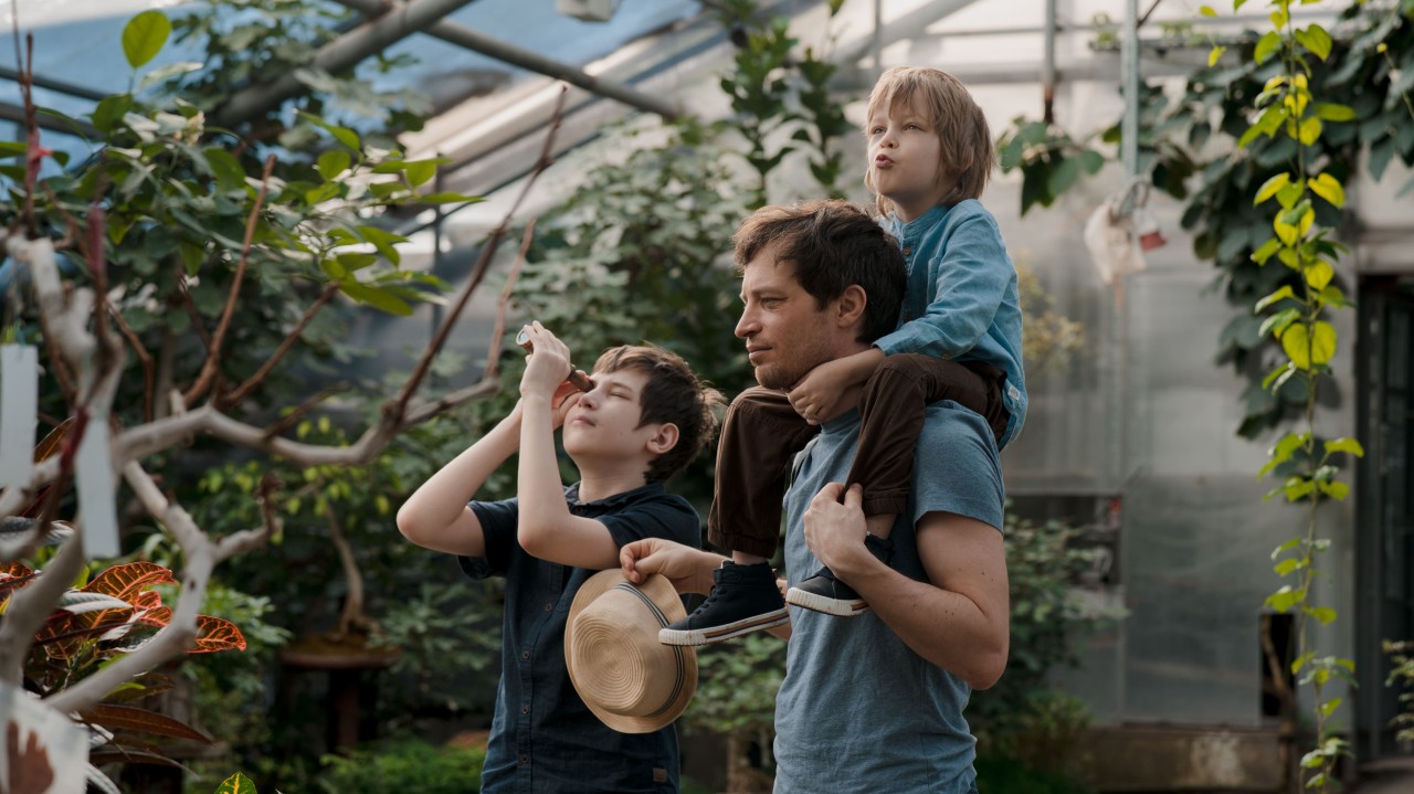 Un padre con sus dos hijos en un invernadero