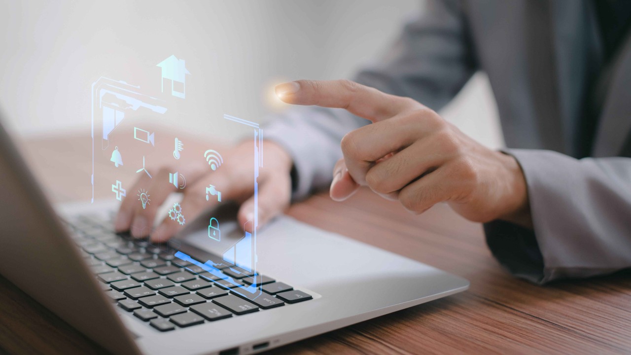 Persona trabajando en un portátil mientras maneja un holograma con el dedo