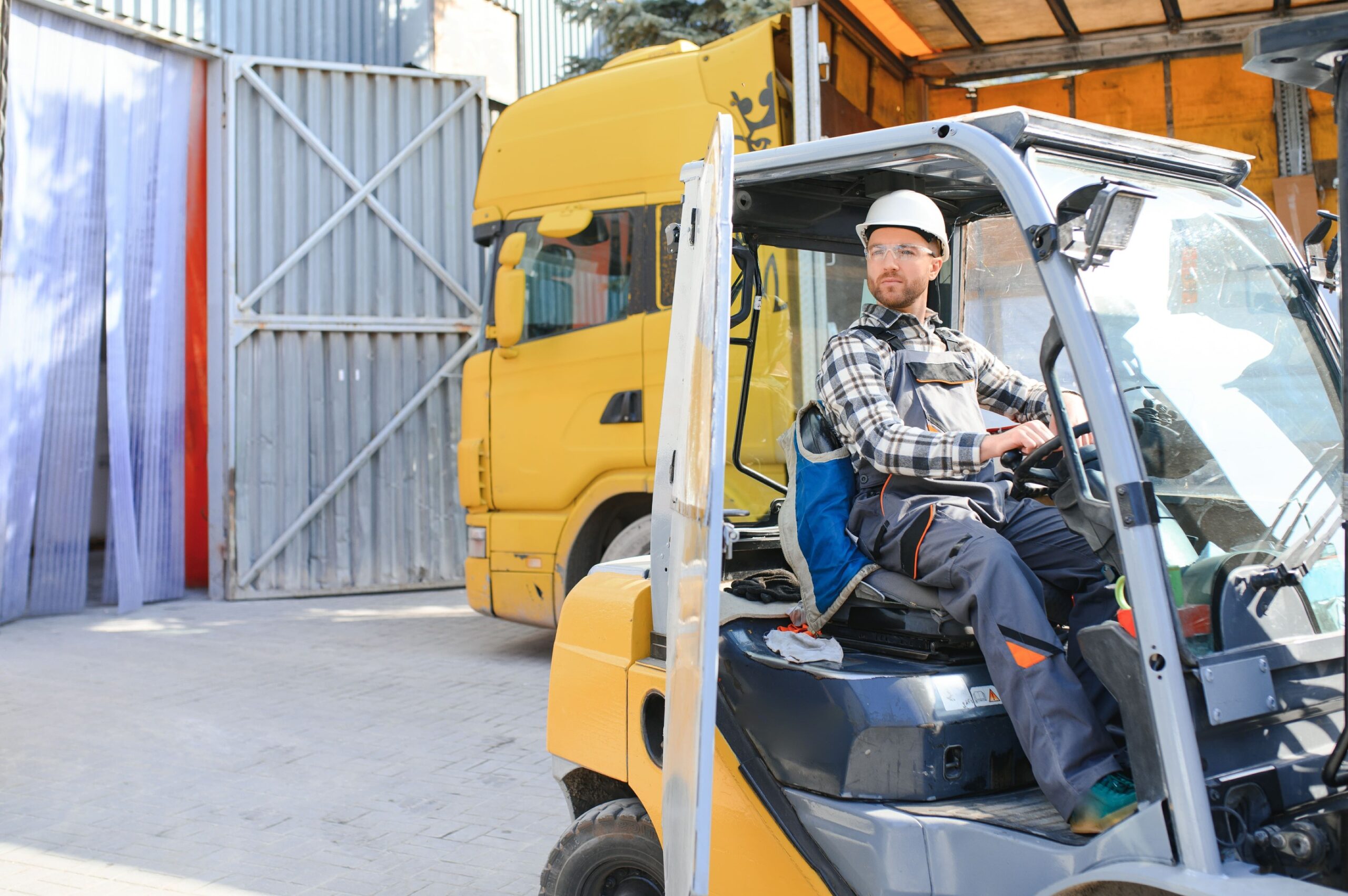 a man in a hard hat sitting on a forklift