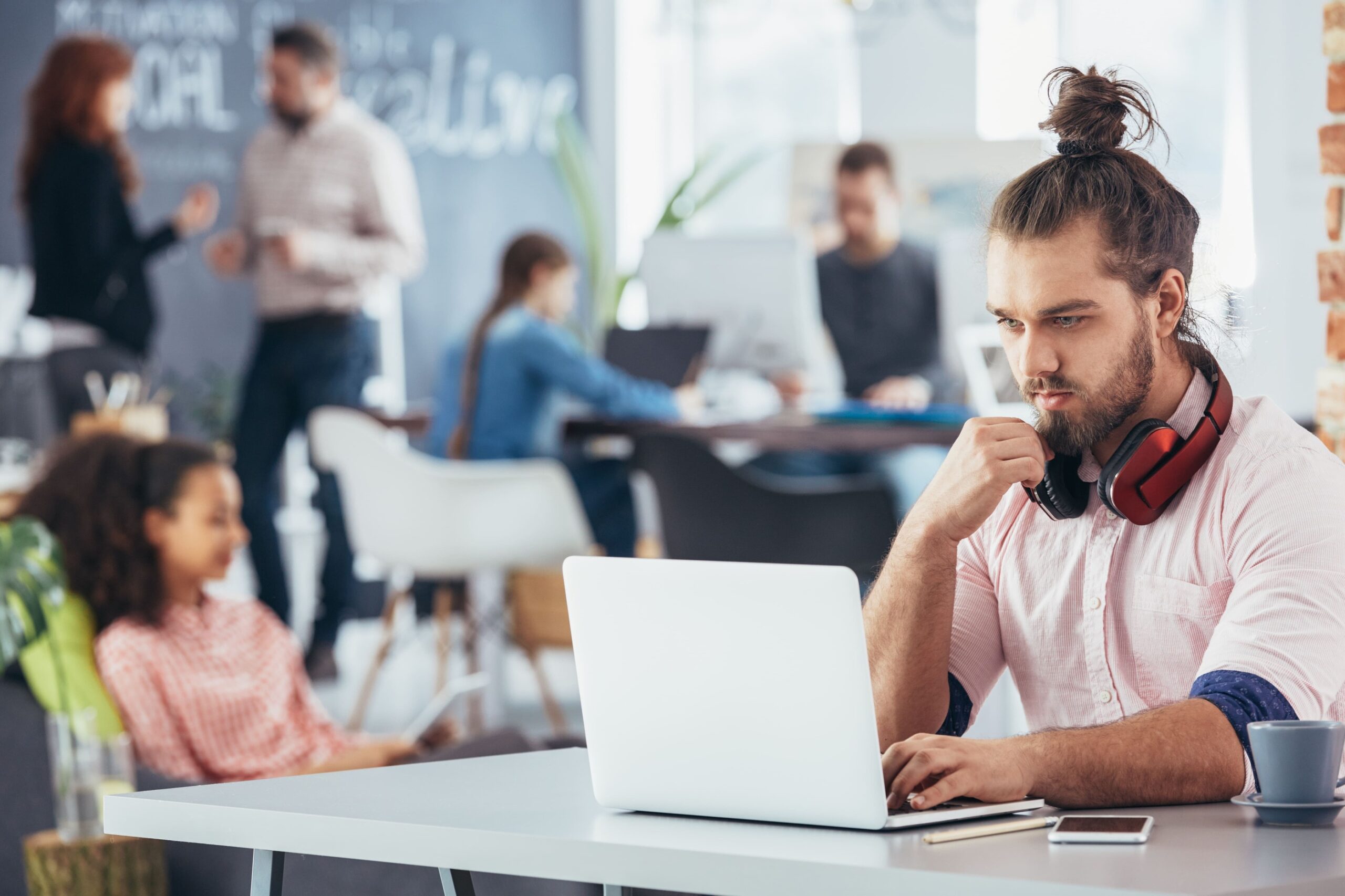 a man with a bun on his head working on a laptop