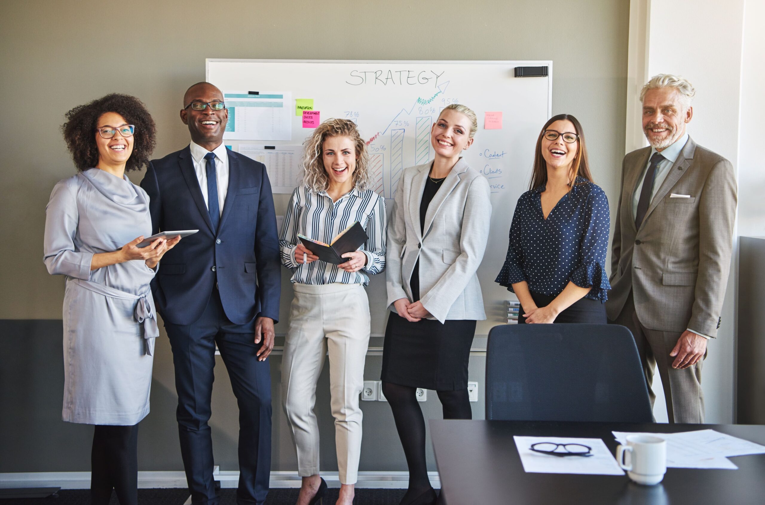 a group of people standing in front of a whiteboard