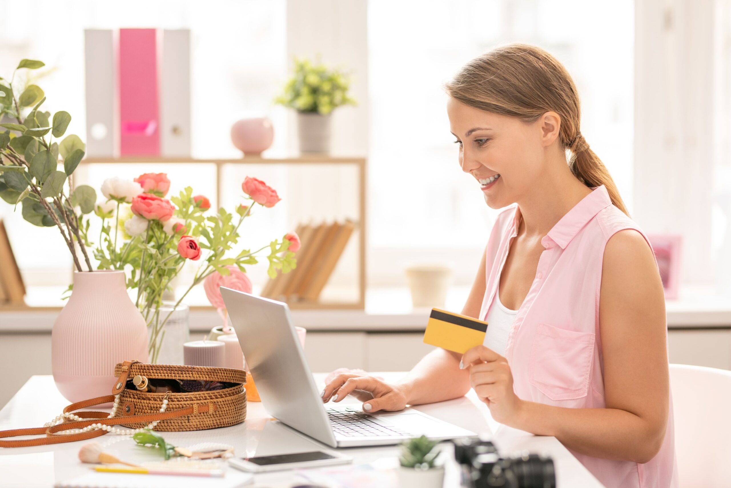 a woman holding a credit card and using a laptop