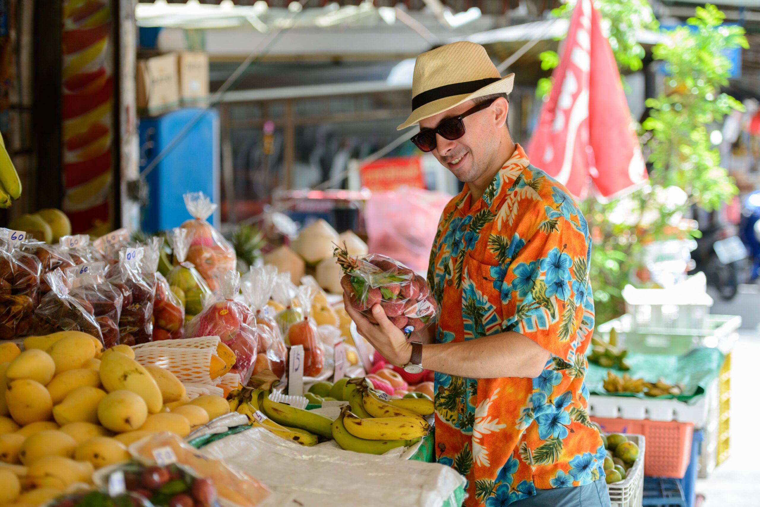 a man in a hat holding a bag of fruit